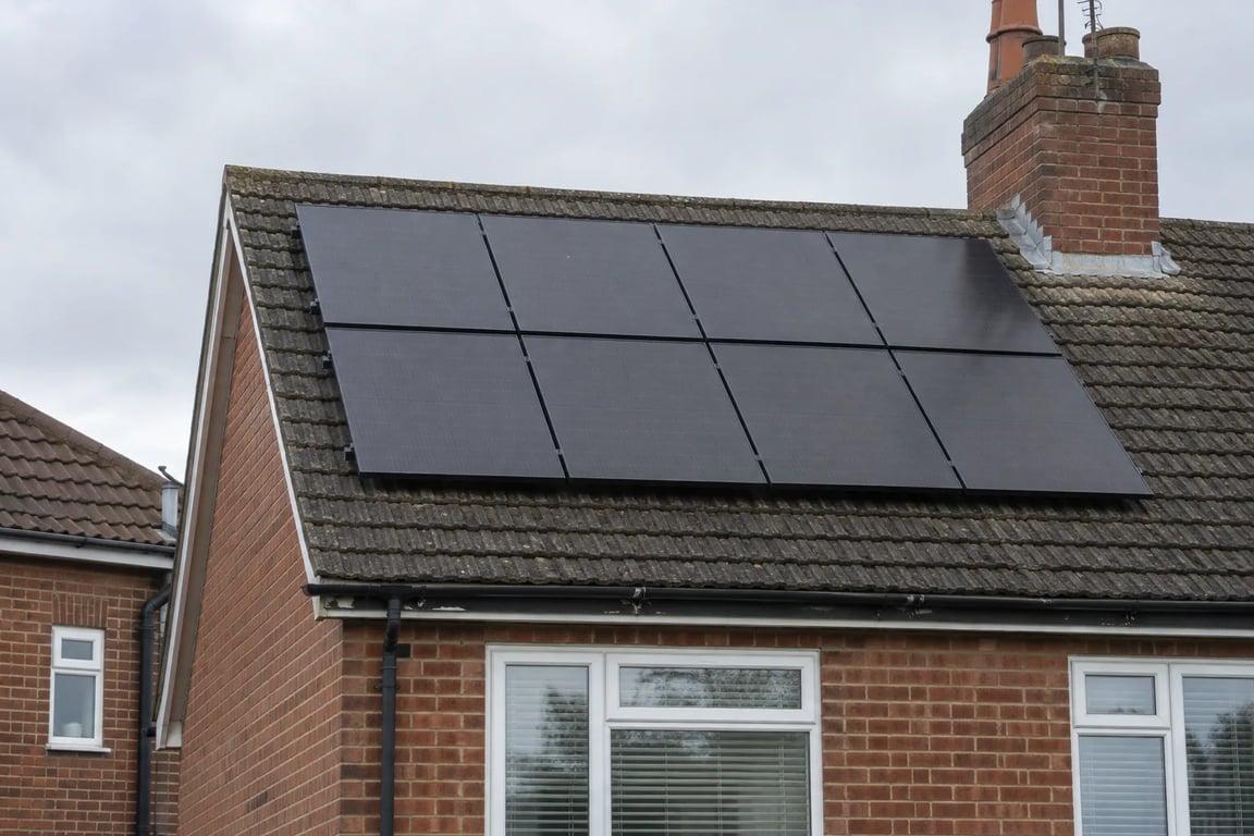 Photographic-style example of black solar panels on a tiled brick house roof.
